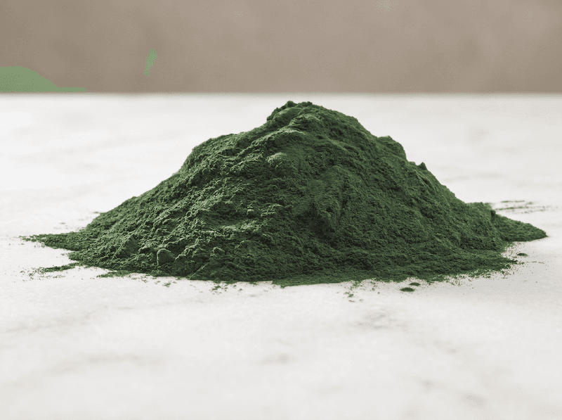 A pile of green organic spirulina green powder
