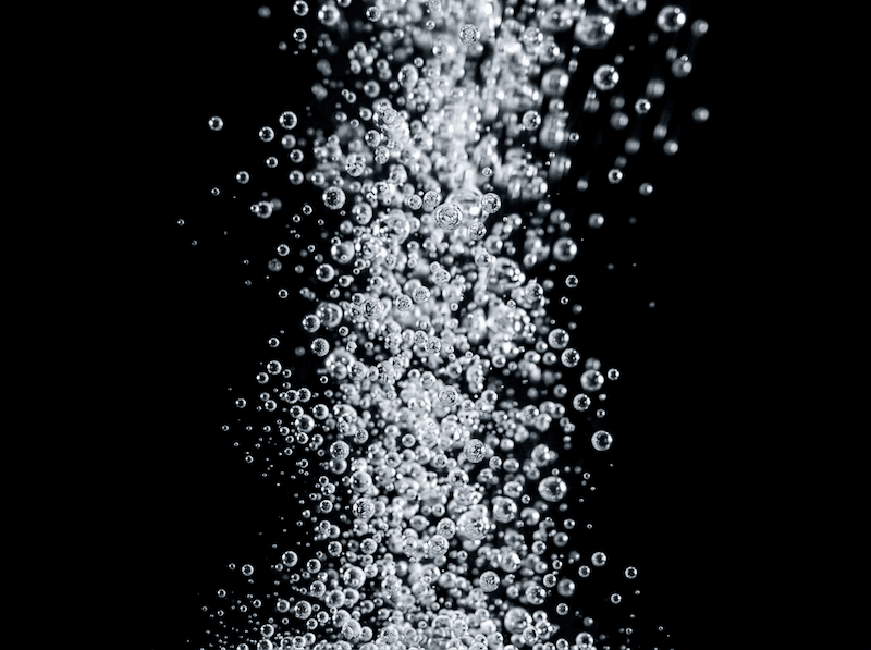 Bubbles from food grade CO2 rising against a black background
